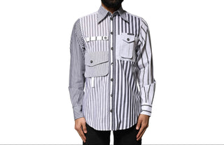 A man wearing a long-sleeve button-up shirt with vertical black and white stripes, featuring a chest pocket with a flap and a horizontal strap detail across the chest.
