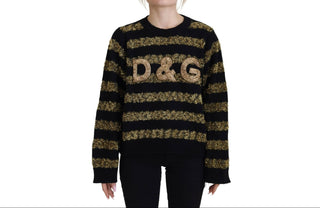 A model wearing a black and gold striped knit sweater with a large gold sequined D&G logo on the chest, paired with black pants, against a plain white background.