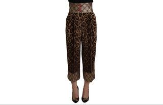A pair of cropped leopard-print pants with a wide patterned waistband and matching cuffs, shown on a white background with a model's legs and black pointed heels visible.