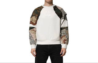 A model wearing a white crewneck sweatshirt with camouflage patterned raglan sleeves and a tonal 'DG' logo on the chest, paired with black pants against a white background.