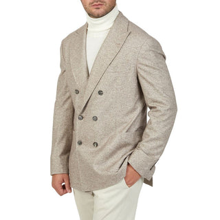 Man wearing a beige double-breasted blazer over a white turtleneck and pants on a white background