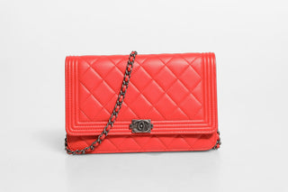 Red quilted handbag with a chain strap on a light gray background