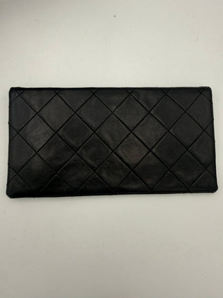 Black quilted clutch bag on a light gray background