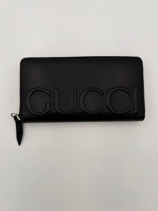 Cartera GUCCI negra con cremallera y logo frontal en relieve