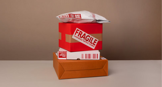 Stack of red boxes with 'Fragile' labels on a neutral background