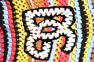 Close-up of a colorful woven pattern with a central white design on a multicolored background.