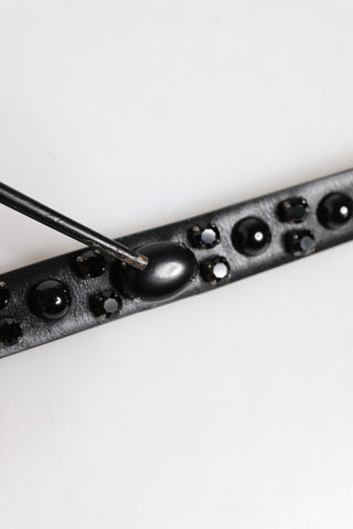 Schwarzer Ledergürtel mit Nieten und Metallschnalle mit Logo
