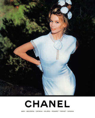 A vintage fashion magazine cover featuring a woman wearing a light blue Chanel dress with a matching floral hair accessory, set against a dark outdoor background, with the Chanel logo printed at the bottom.