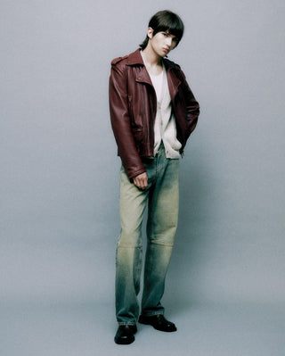 Person wearing a brown leather jacket and green pants on a gray background