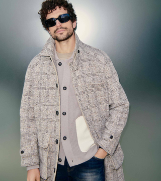 Man wearing a long coat and sunglasses.