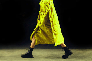 Person wearing a bright yellow coat walking on a dark background