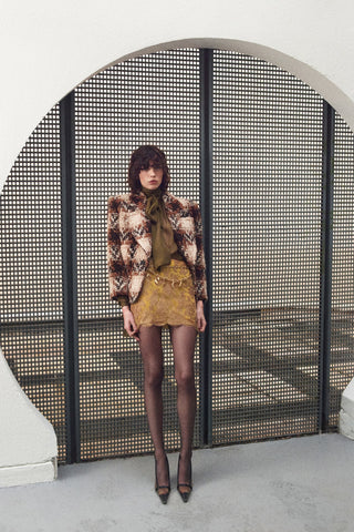 Woman in a stylish outfit standing in front of a textured wall.