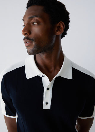 Man wearing a black and white polo shirt against a plain background