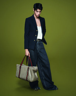 Man holding a Gucci bag against a green background