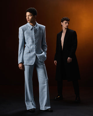 Two men in formal attire standing against a gradient background